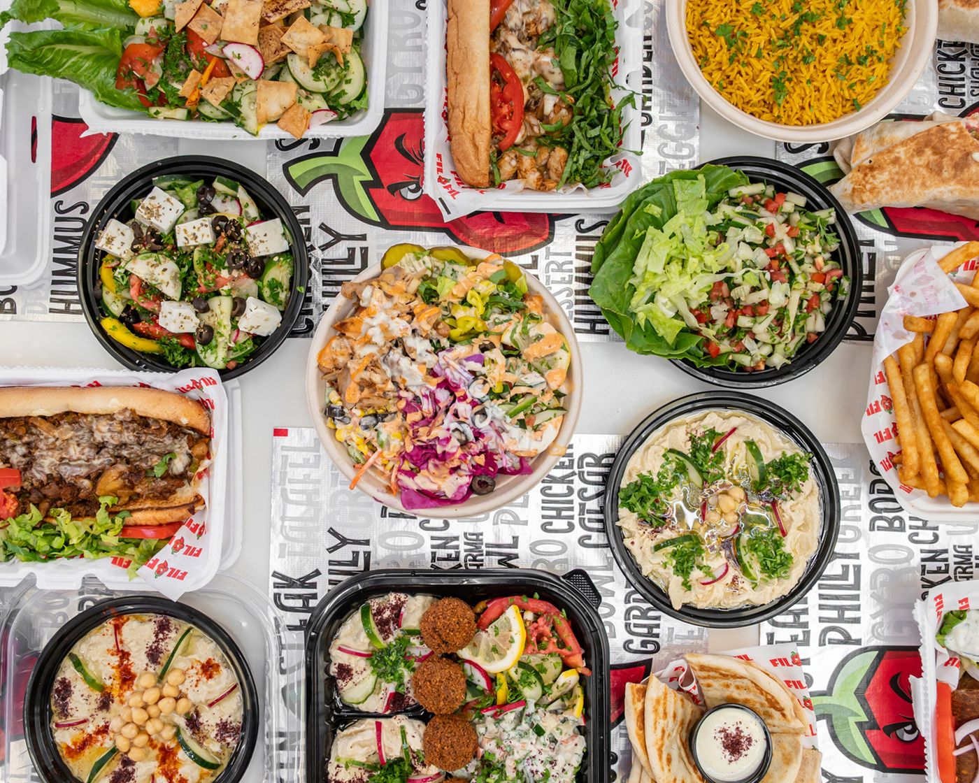A spread of FiL FiL bowls, sandwiches, hummus and fries